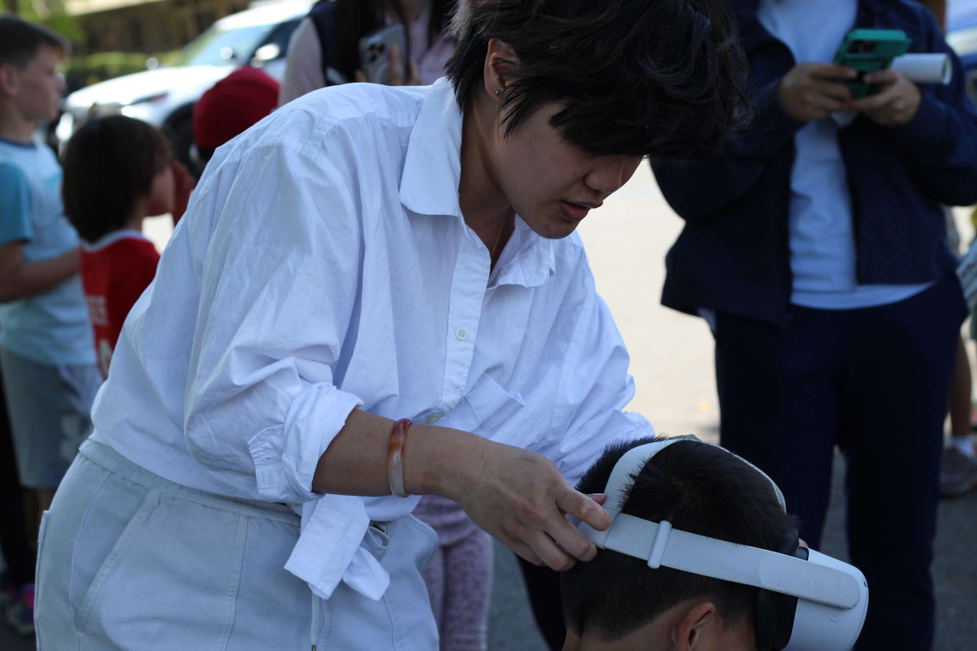 Aimie, Nguyen, undergraduate research assistant, helps a child put on a virtual reality headset