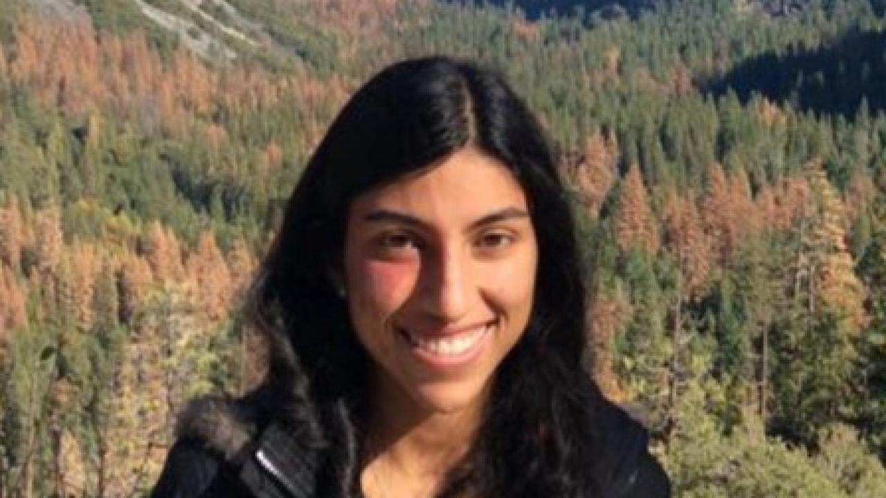 Headshot of Camila Alviar. Redwood trees are behind Camila, in the distance
