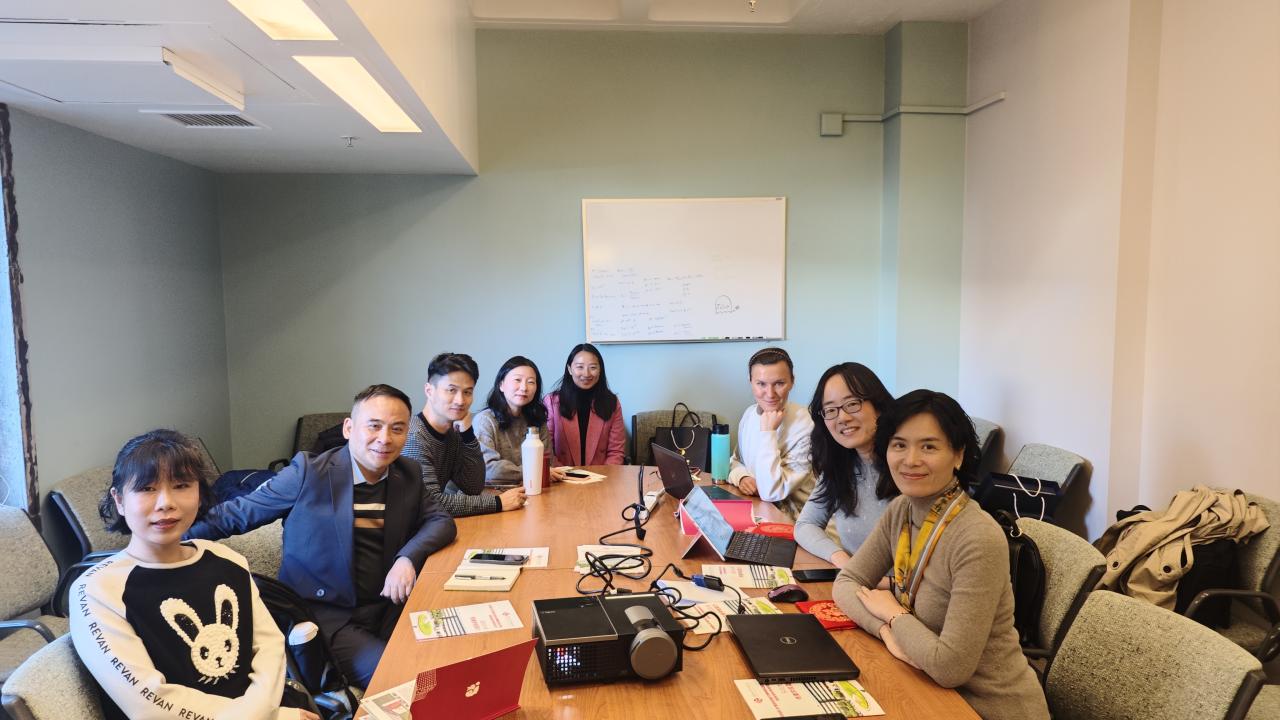 Members of the Shenzhen University Delegation and the UC Davis Department of Communication sit around a conference room table, facing the camera, and smiling.