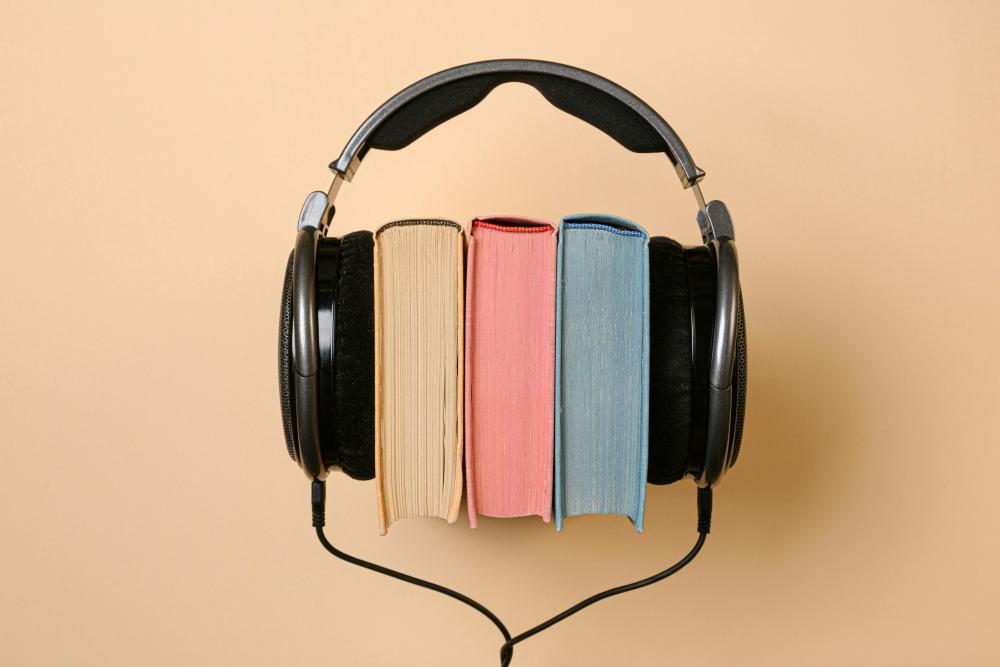 Three books are placed between over-the-ear headphones
