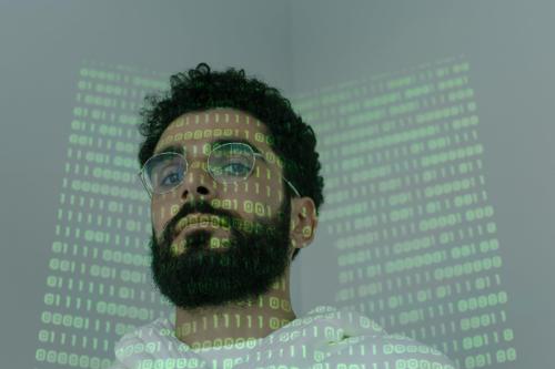 Man with glasses. Ones and zeros, like binary code, are projected onto his face.