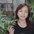 Trisha Lin standing in front of a plant 