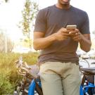 Person Leaning on Bike While Holding Smartphone